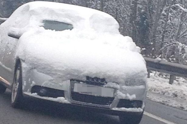 A+car+driving+on+the+road+whilst+covered+in+snow+with+only+a+peephole+for+the+driver+to+see+out+of